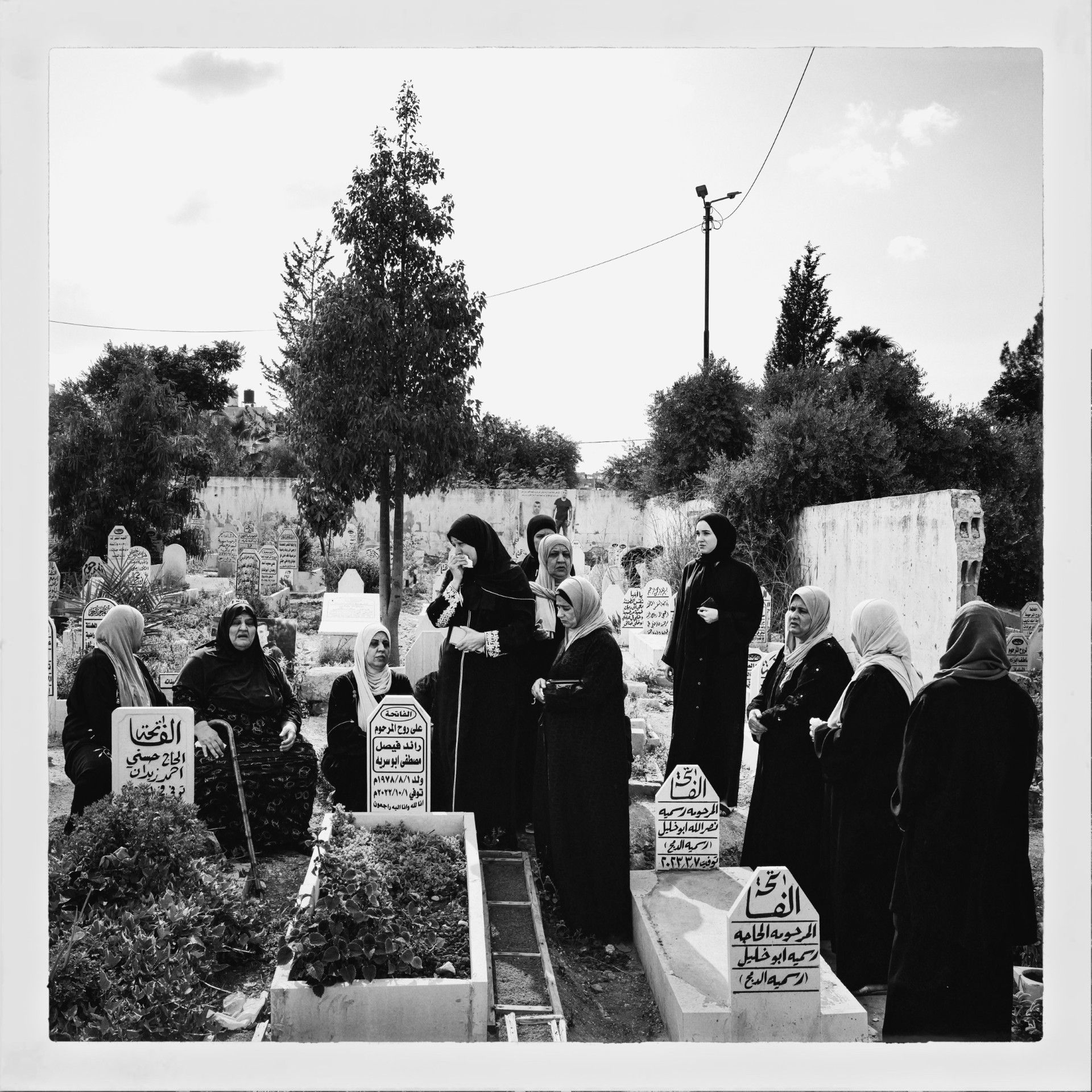 A group of women at a graveyard grieving nearby a grave