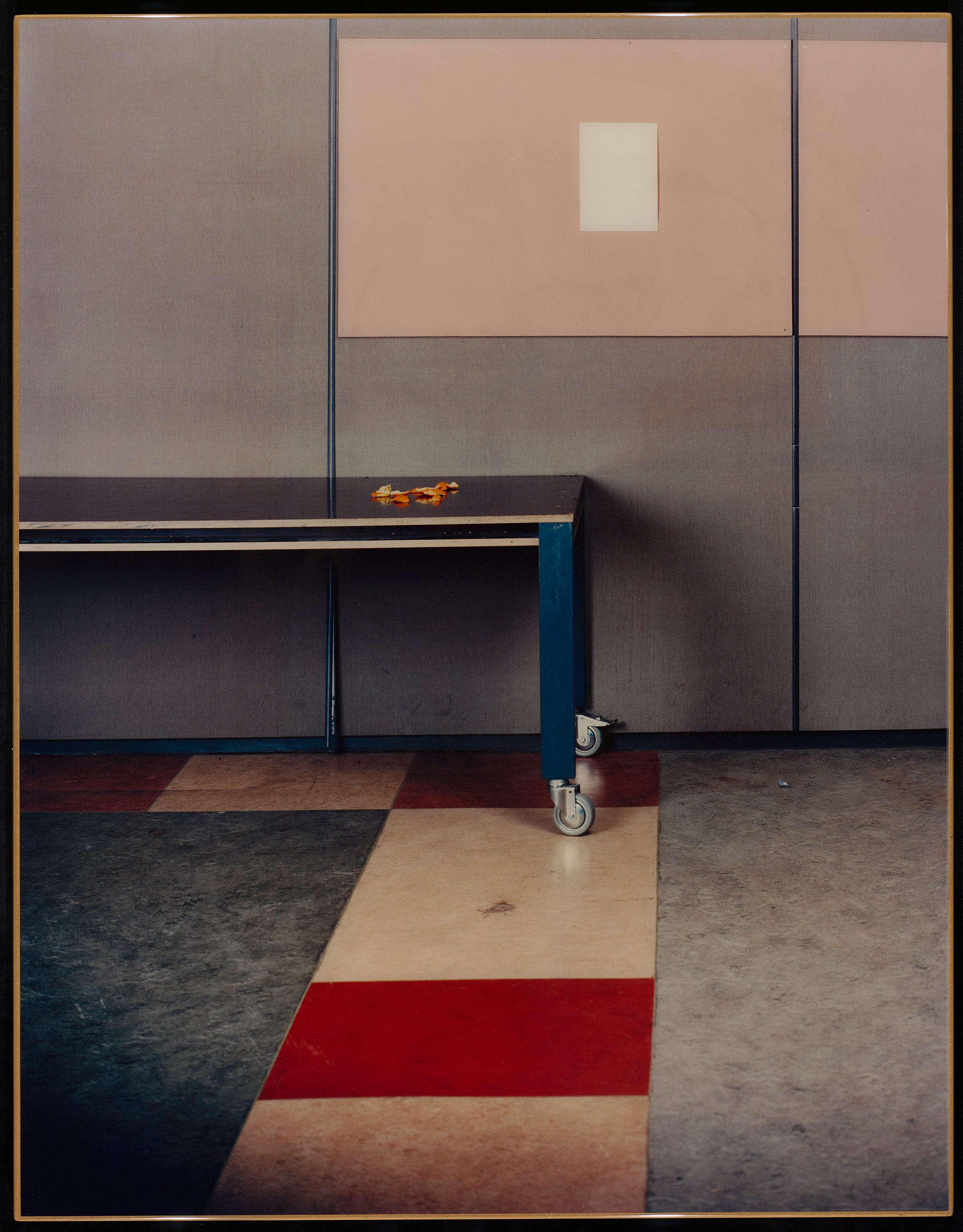 Table in room with gray and pink and white color areas as wall, and gray, red and beige color areas on the floor