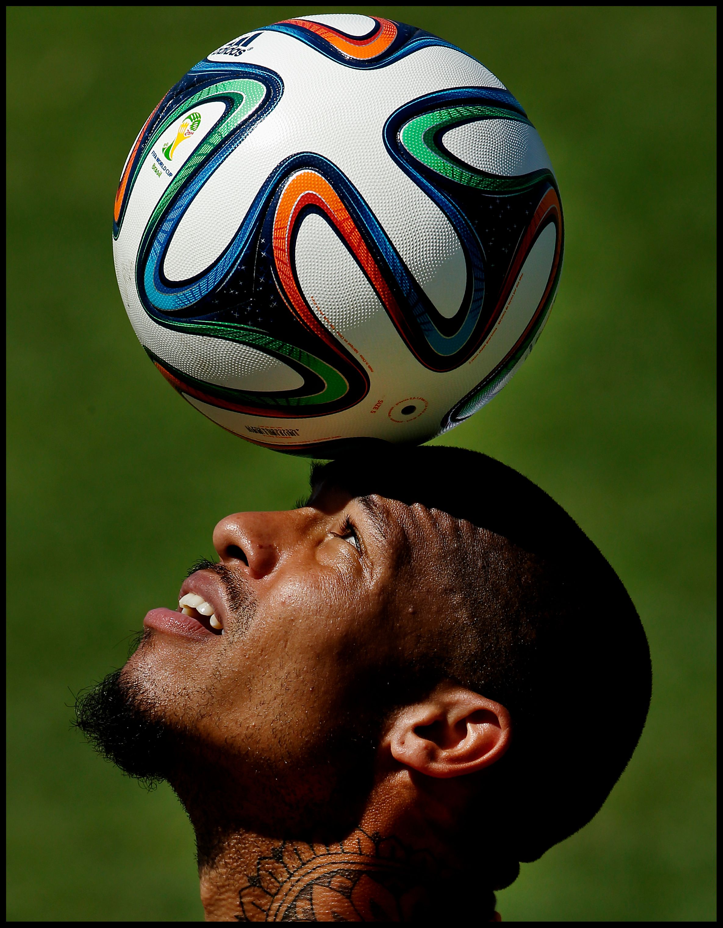 Close-up of a someone playing football, balancing a ball on his head.