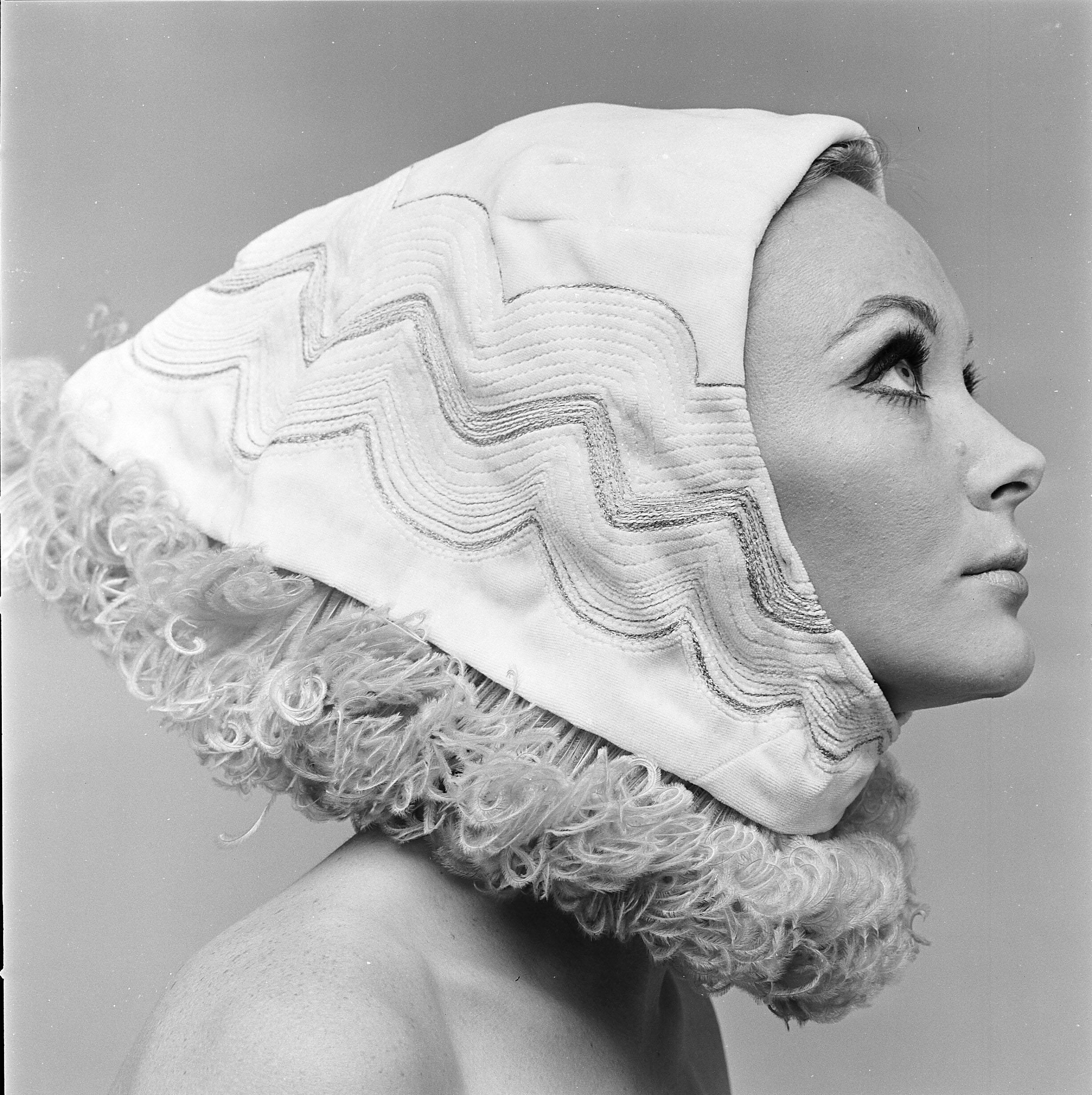 Closeup of a woman in black and white, wearing a headpiece that covers her hair.