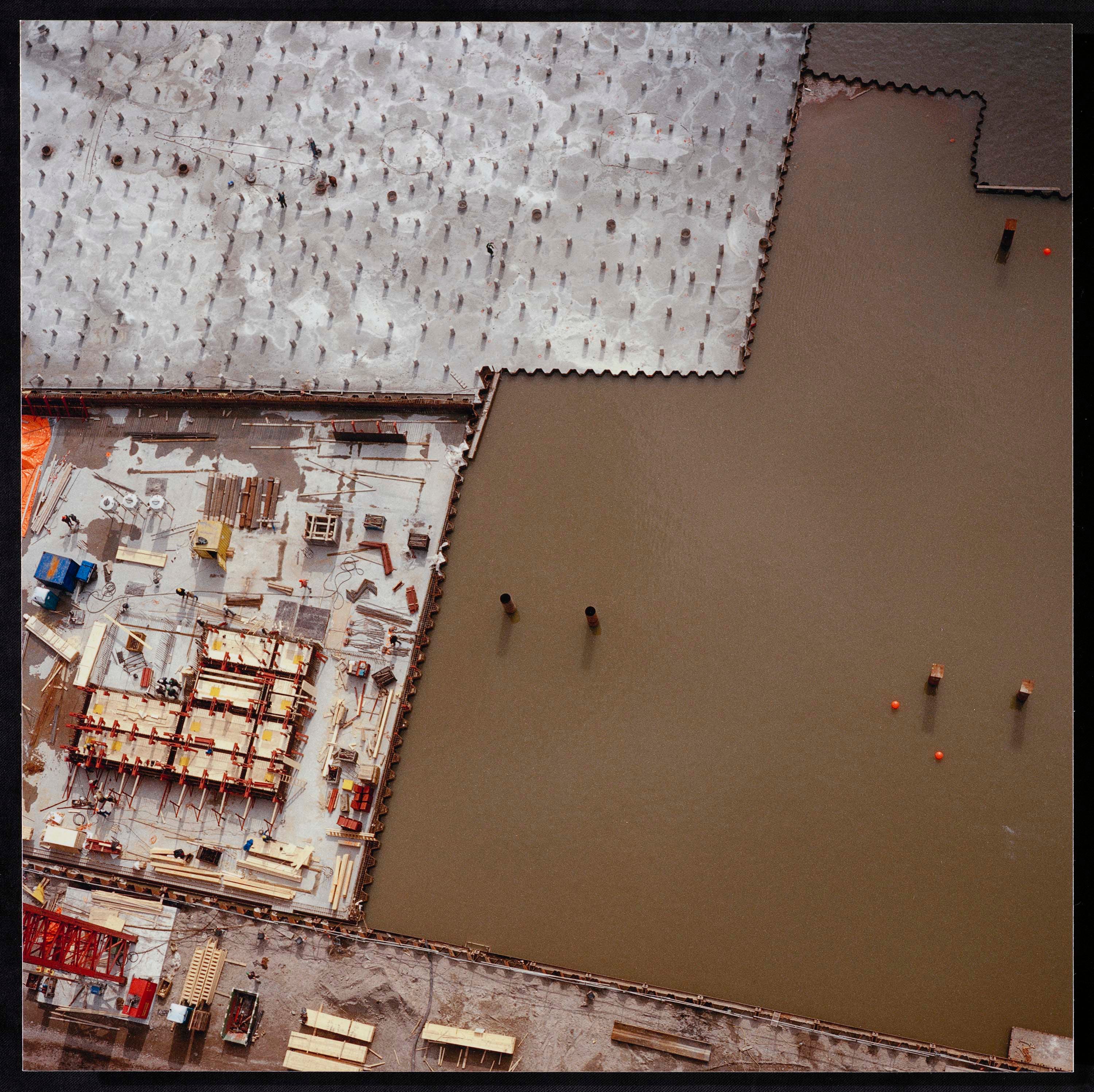 Aerial photo of a construction site on the left, water visible on the right