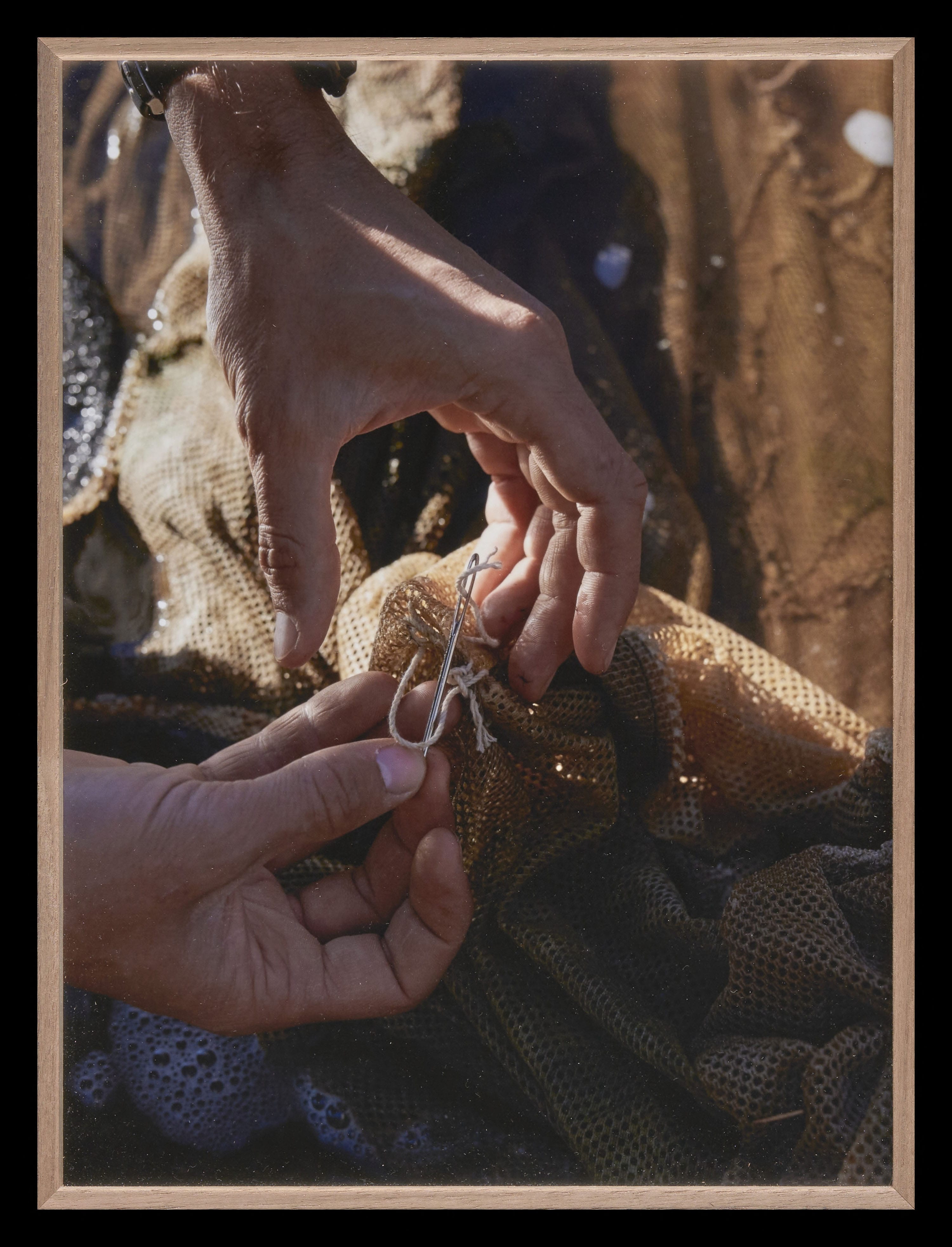 A close-up of two hands repairing a net.