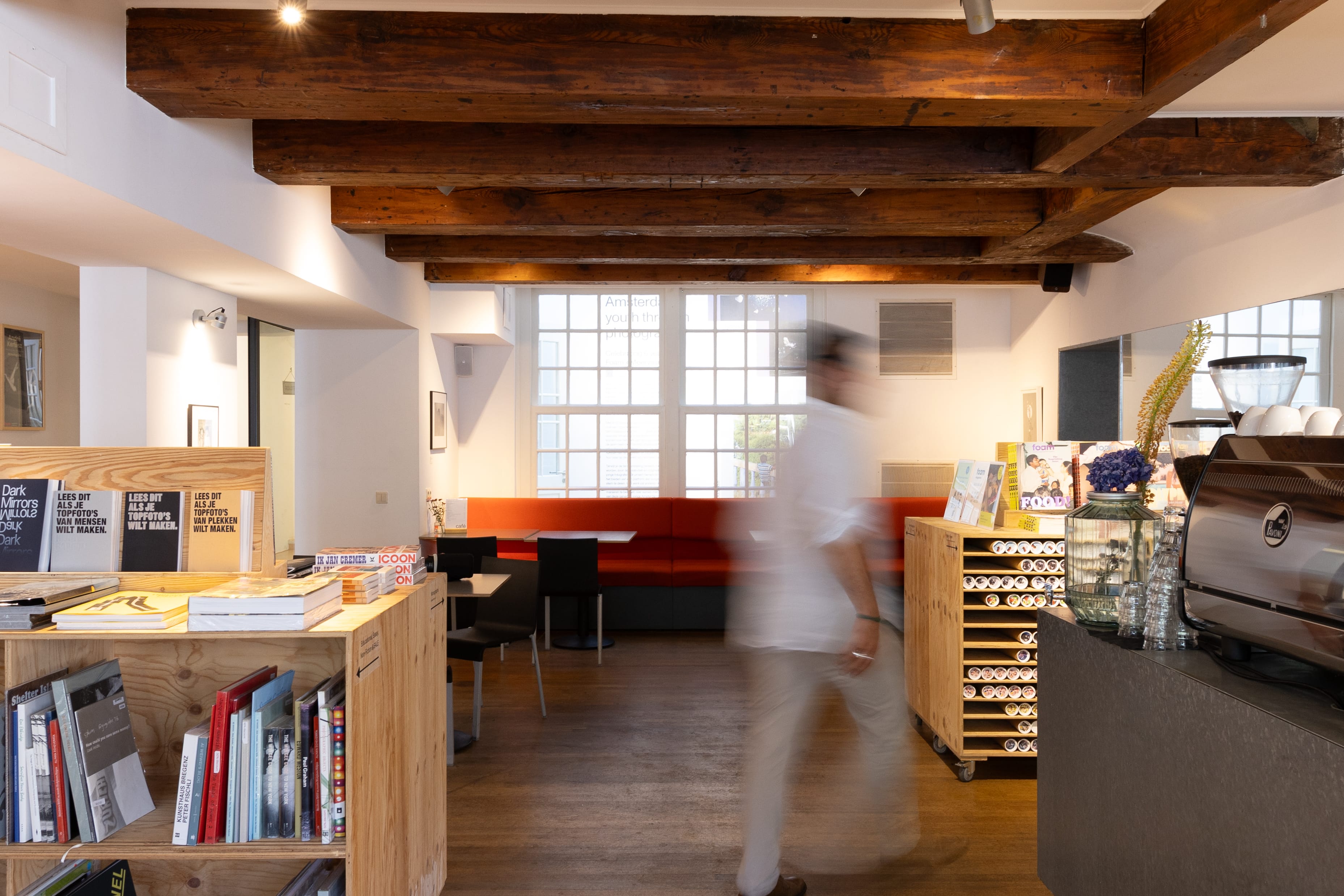 Cozy looking cafe with books and a coffee machine.