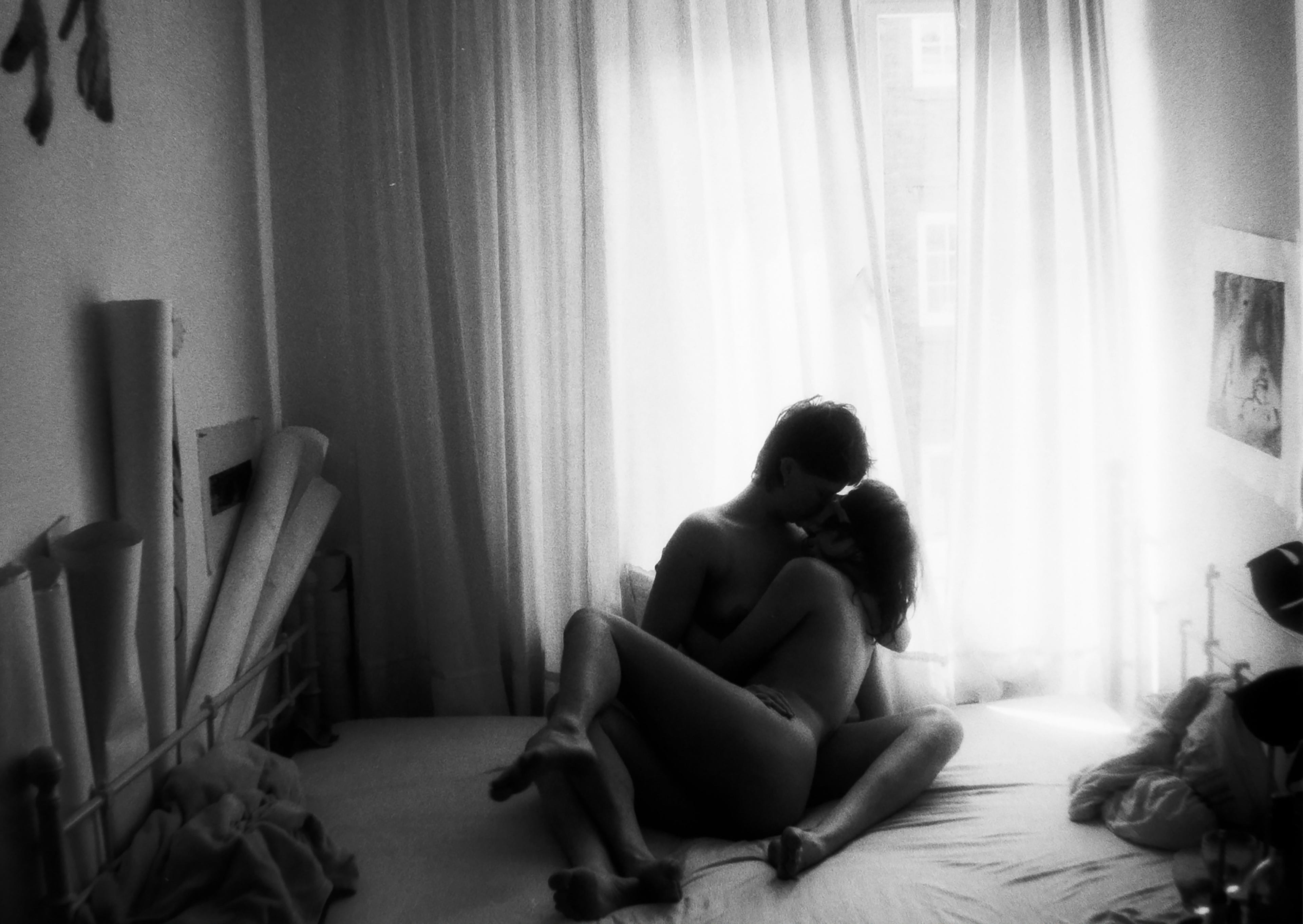 Two people naked kissing in a bedroom BW