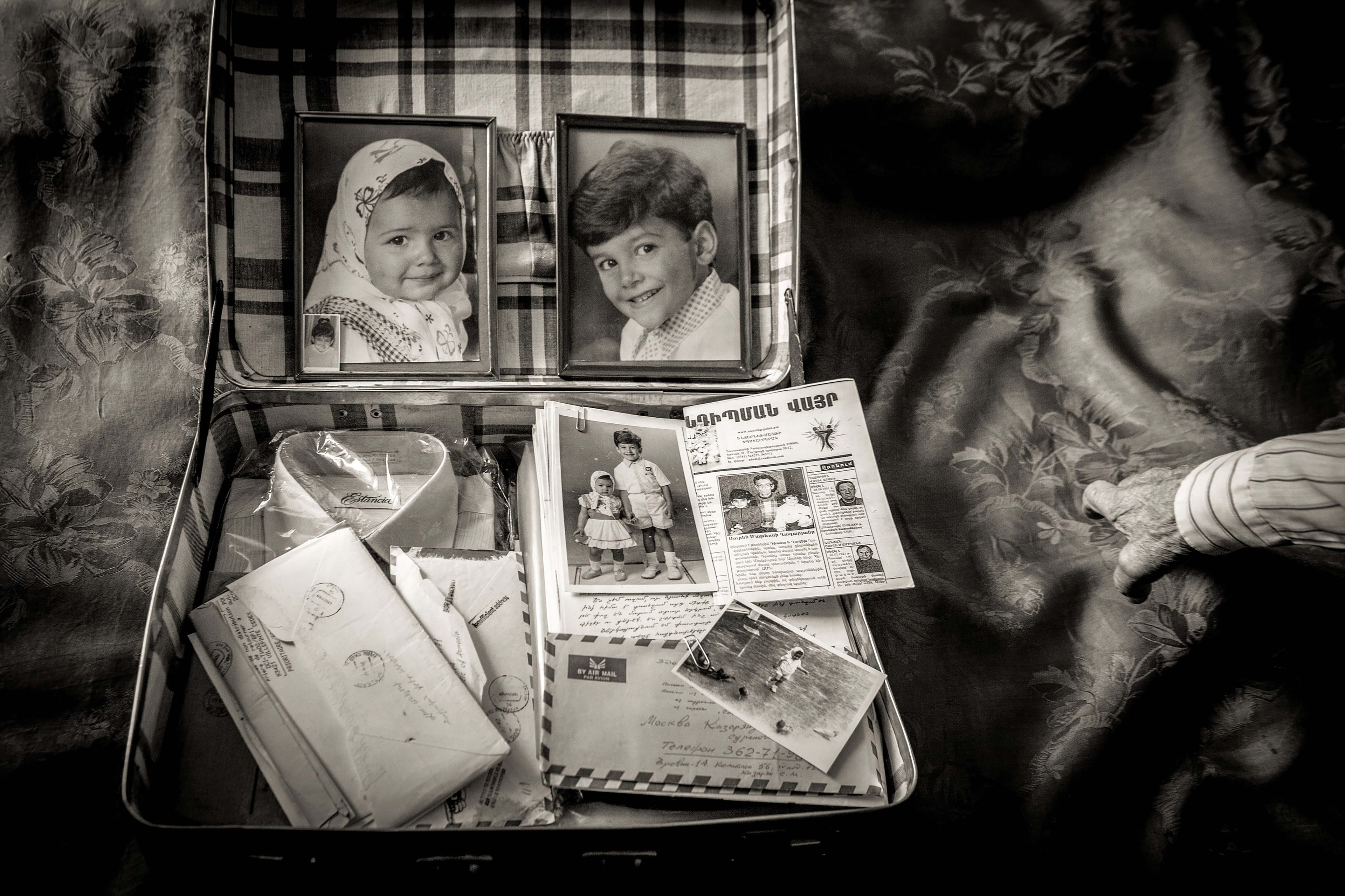 A small opened suitcase showing two framed portraits of children inside