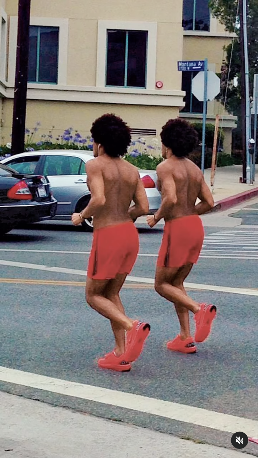 Image of two identically-looking men running on a street in red pants and red shoes.